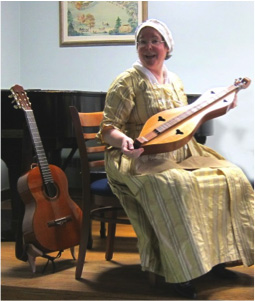 Diane Taraz, Director of the Colonial Singers, displaying the dulcimer, one of the typical musical instruments used in the 1700's.